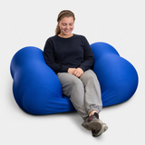 Person sitting on a large blue Squeeze Me Deep Pressure cushion against a white background