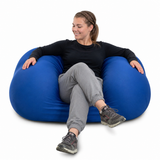 Woman sitting on a blue Squeeze Me Deep Pressure cushion against a white background
