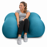 Woman sitting on a large Squeeze Me Deep Pressure cushion against a white background