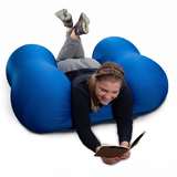Person lying on a blue Squeeze Me Deep Pressure cushion reading a book