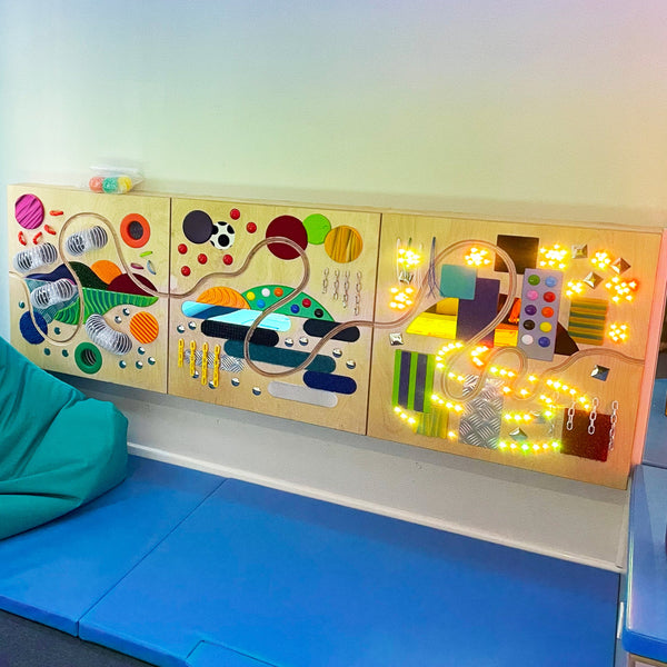 Educational wall panel with colorful shapes and lights on a blue mat